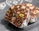 Dwa kawałki blok czekoladowy przepis babci, pełne orzechów i ciastek, posypane cukrem pudrem.