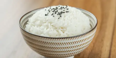 Miseczka puszystego ryżu basmati, posypana czarnym sezamem. Idealny przykład, jak ugotować ryż basmati.