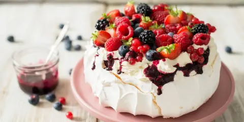 Beza pavlova która zawsze wychodzi, udekorowana bitą śmietaną i mnóstwem świeżych owoców leśnych.