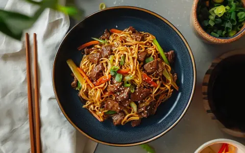 Makaron chow mein z wołowiną i warzywami w misce, obok pałeczek i sosu sojowego.