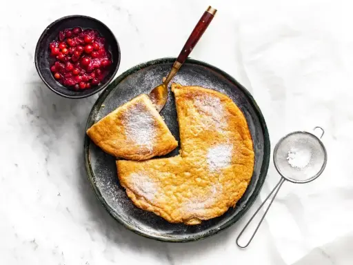Puszysty omlet z airfryer, posypany cukrem pudrem, podany z żurawiną. Idealny na śniadanie.