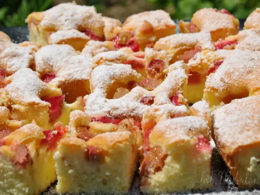 Szybkie ciasto z rabarbarem, posypane cukrem pudrem, wygląda apetycznie. Idealne na letnie popołudnie.