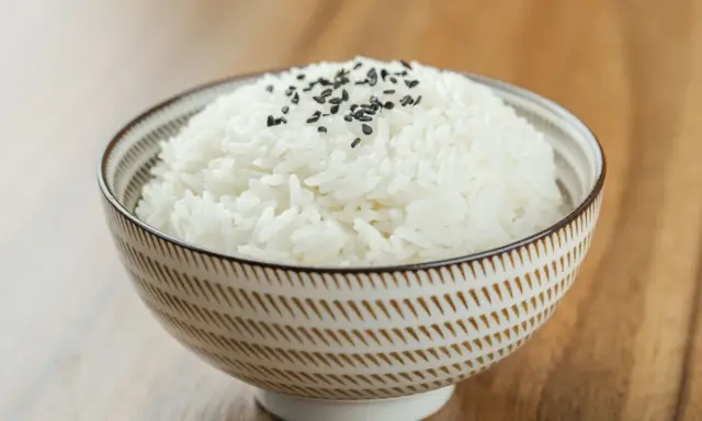 Miseczka puszystego ryżu basmati, posypana czarnym sezamem. Idealny przykład, jak ugotować ryż basmati.