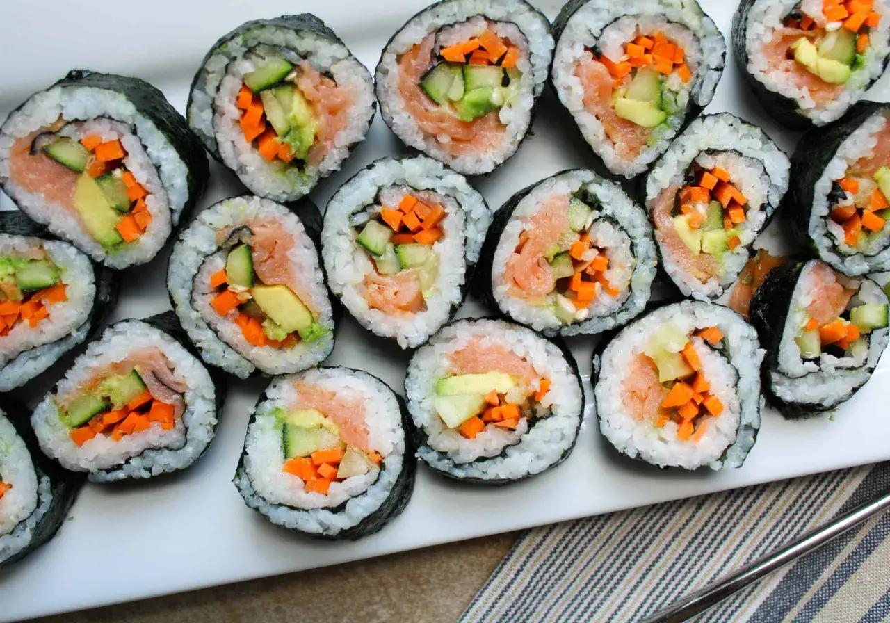 Pyszne rolki sushi z łososiem, awokado, ogórkiem i marchewką. Idealne na lunch lub kolację.