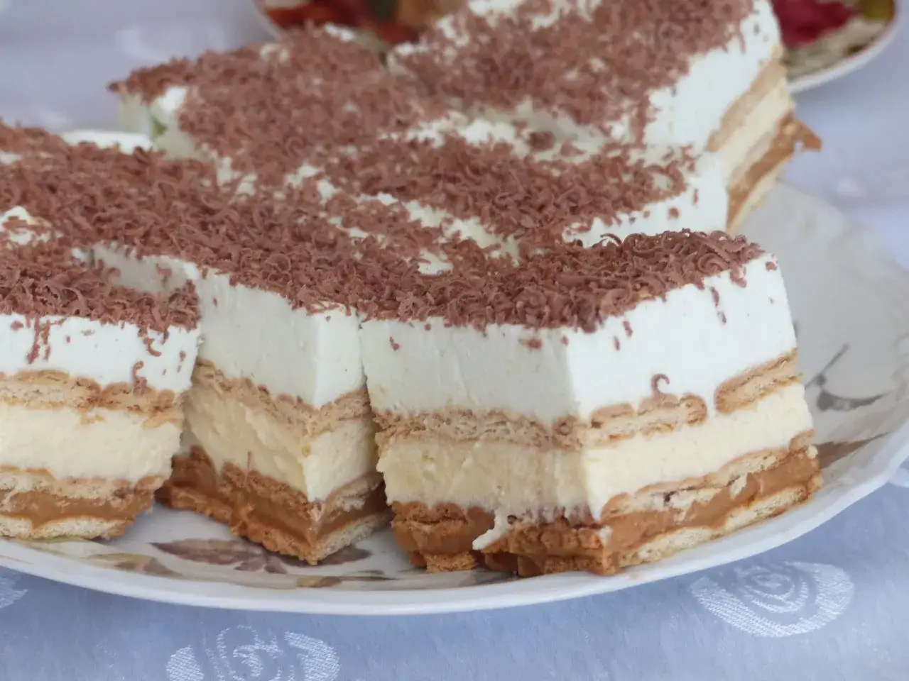 Szybkie ciasto bez pieczenia z budyniem i herbatnikami, udekorowane wiórkami czekolady. Idealne na deser!